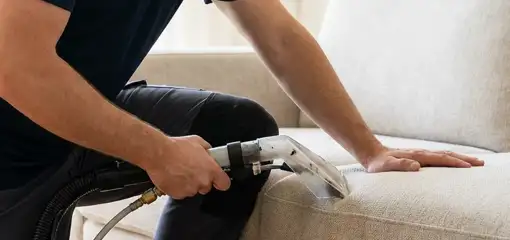 Professional upholstery cleaner deep-cleaning a fabric sofa with a handheld extraction tool, Tuscaloosa, AL.